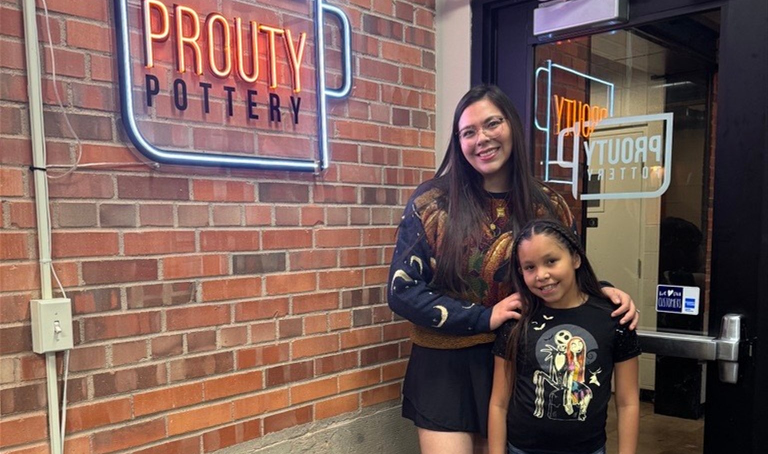 Big Sister Victoria and Little Sister Jalyssa smiling outside Prouty Pottery